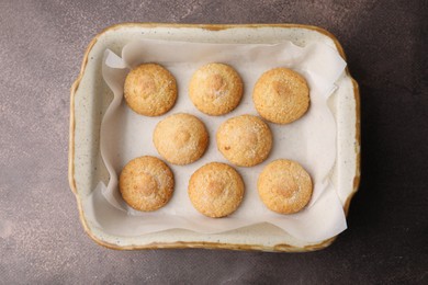 Photo of Tasty sweet sugar cookies in baking dish on brown table, top view