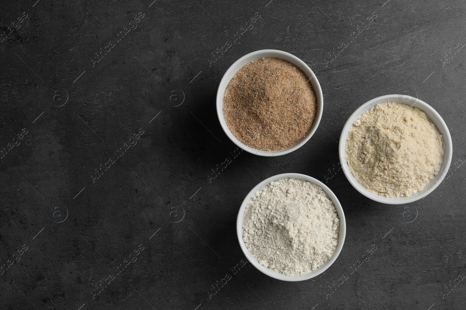 Photo of Bowls with different types of flour on grey background, top view. Space for text