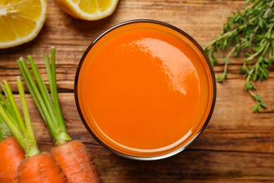 Photo of Glass of tasty carrot juice on wooden table, flat lay