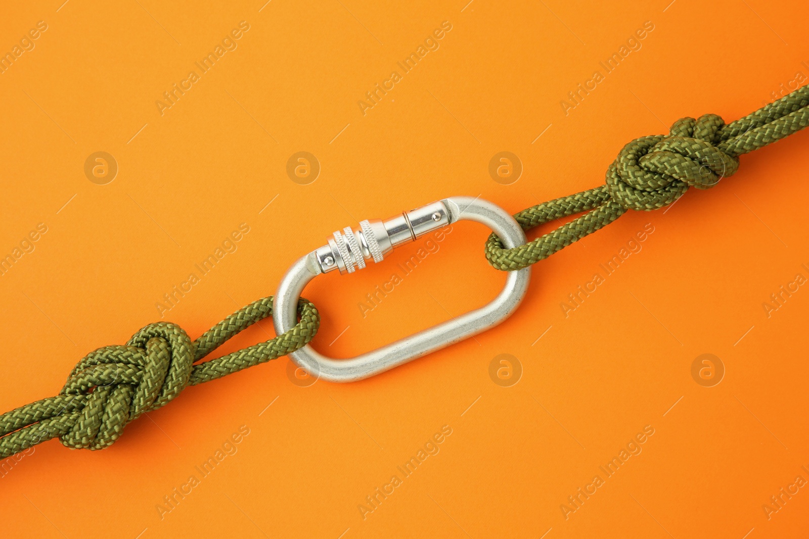 Photo of One metal carabiner with ropes on orange background, top view