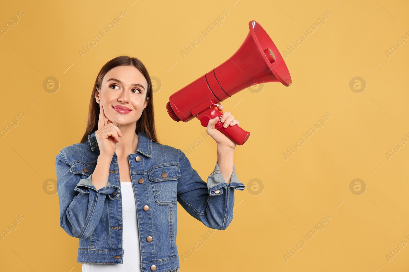 Photo of Young woman with megaphone on yellow background. Space for text