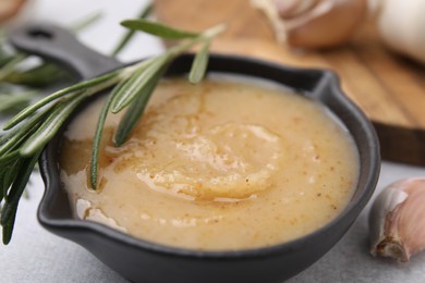 Photo of Delicious turkey gravy, rosemary and garlic on table, closeup