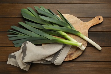 Photo of Fresh raw leeks on wooden table, flat lay