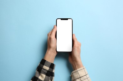 Photo of Woman with smartphone on light blue background, top view