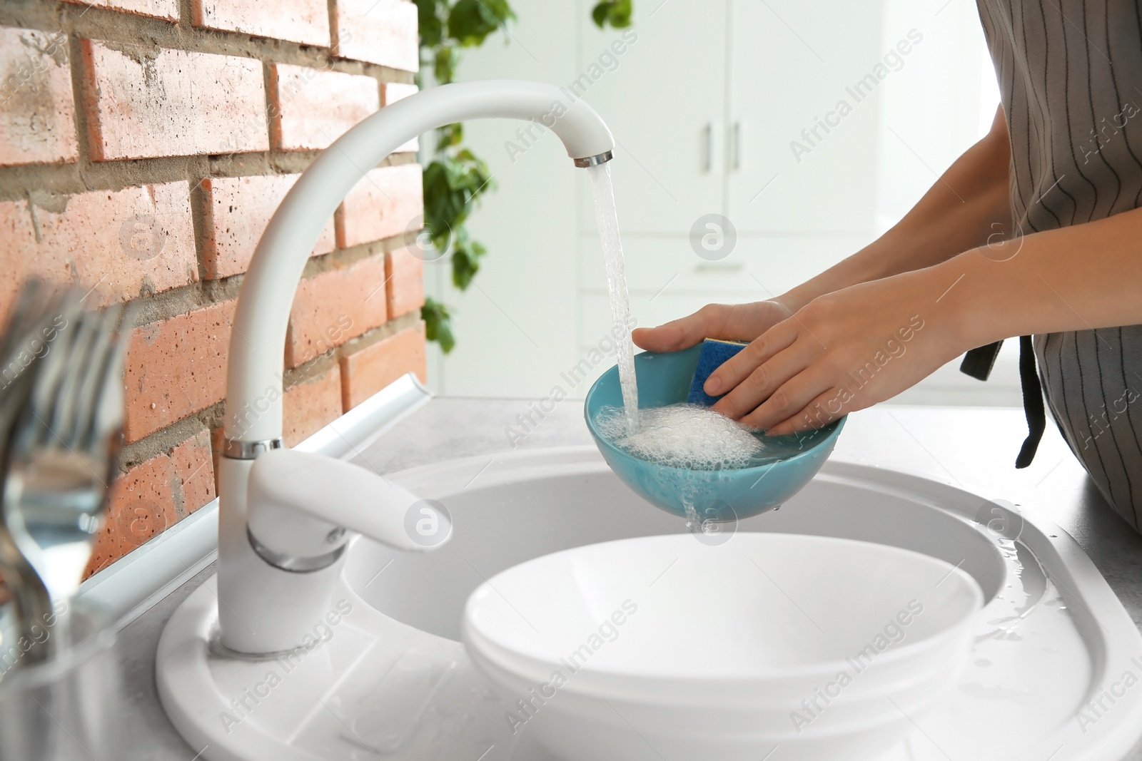 Photo of Woman washing dishes in kitchen sink, closeup view. Cleaning chores