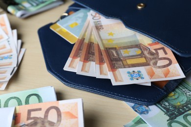 Wallet and different Euro banknotes on wooden table, closeup. Money exchange