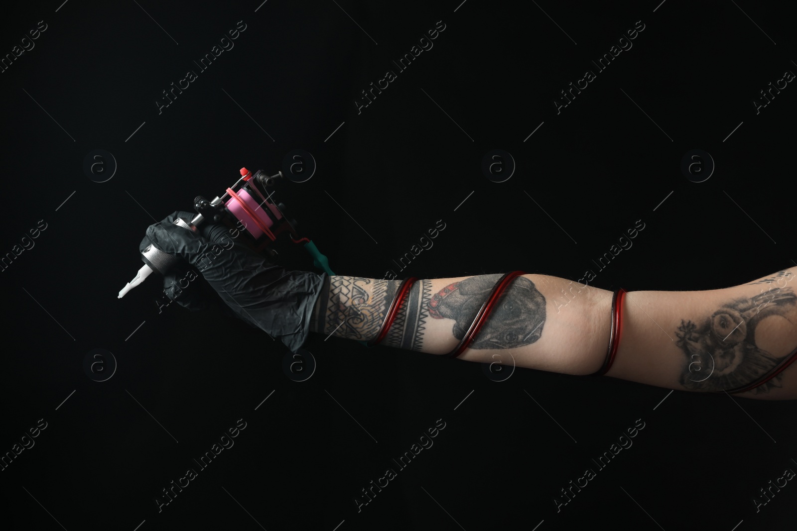 Photo of Tattoo artist with professional machine on black background, closeup