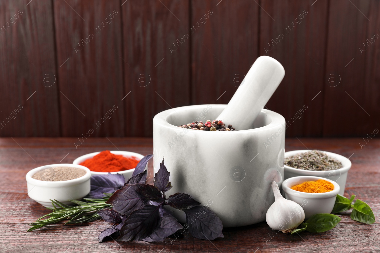 Photo of Mortar and different spices on wooden table