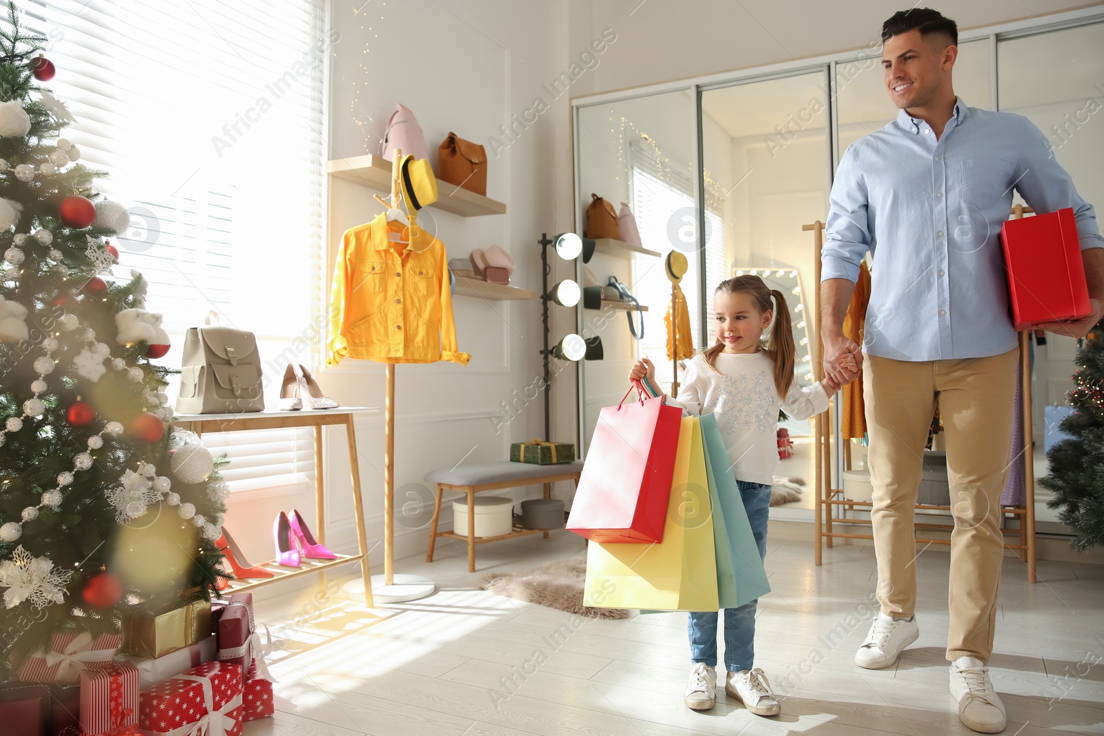 Photo of Father and daughter with bags in store. Family Christmas shopping