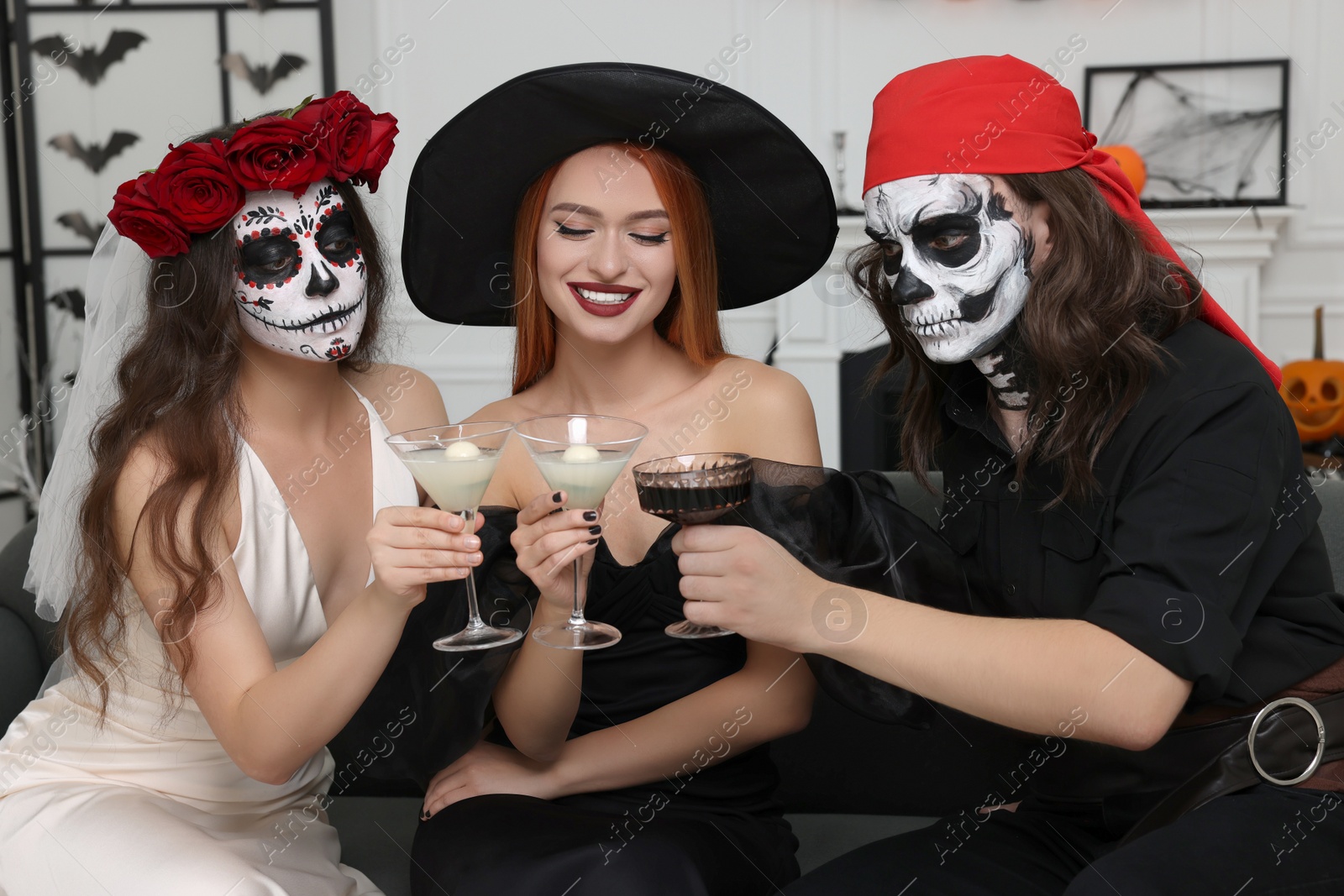 Photo of Group of people in scary costumes with cocktails celebrating Halloween indoors