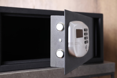 Photo of Black steel safe with electronic lock on grey table, closeup