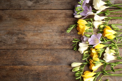 Photo of Beautiful fresh freesia flowers on wooden background, flat lay. Space for text