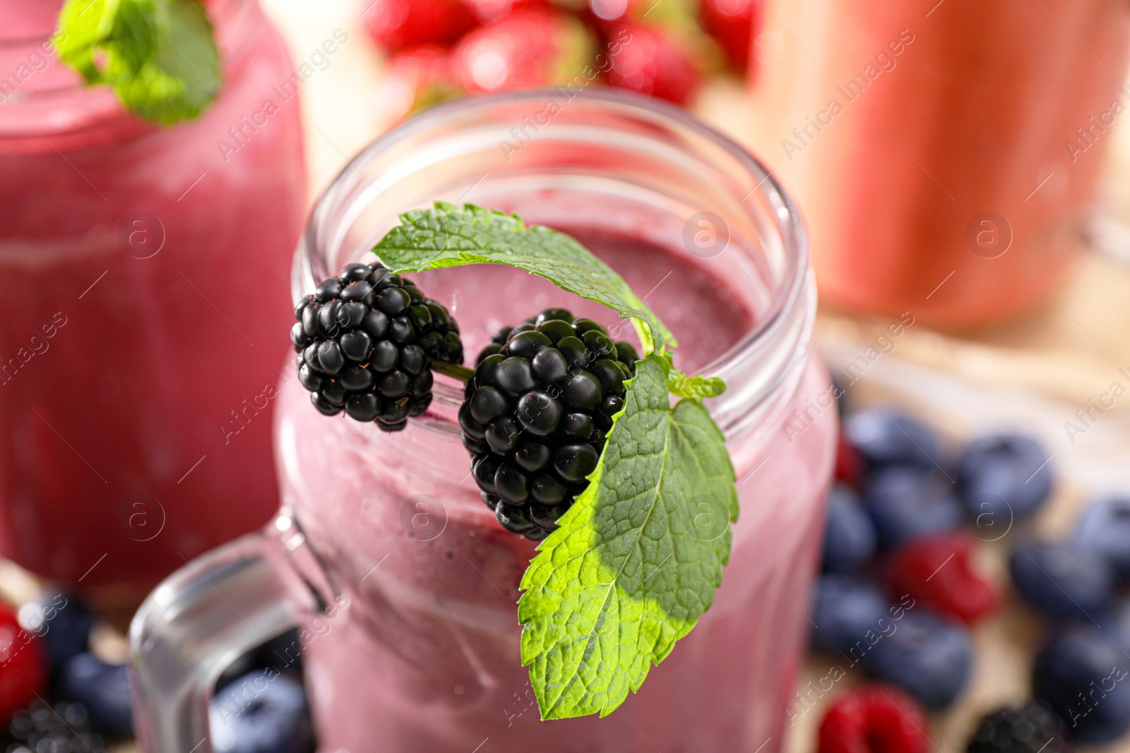 Photo of Mason jar of tasty smoothie with fresh blackberry and mint, closeup