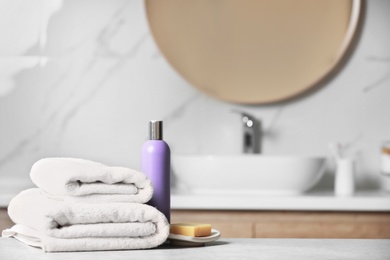 Folded towels and toiletries on marble table in bathroom, space for text