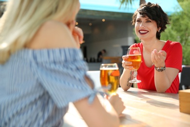 Photo of Young women with glasses of cold beer at table