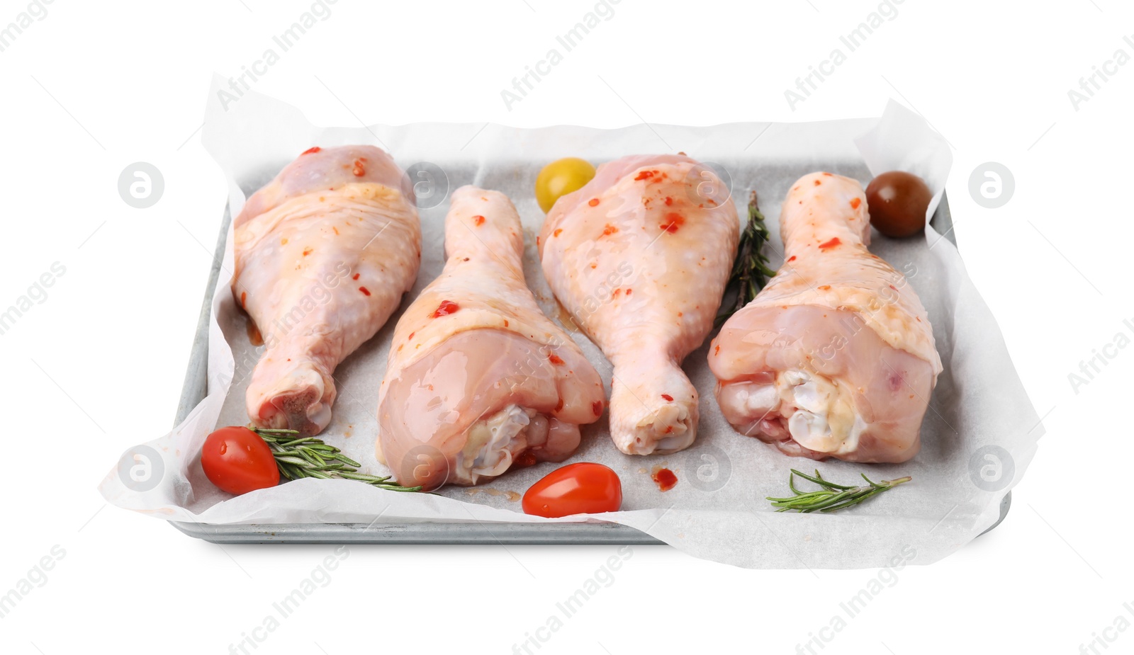 Photo of Raw marinated chicken drumsticks, rosemary and tomatoes in baking dish isolated on white
