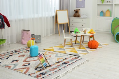 Photo of Child`s playroom with different toys and modern furniture. Stylish kindergarten interior