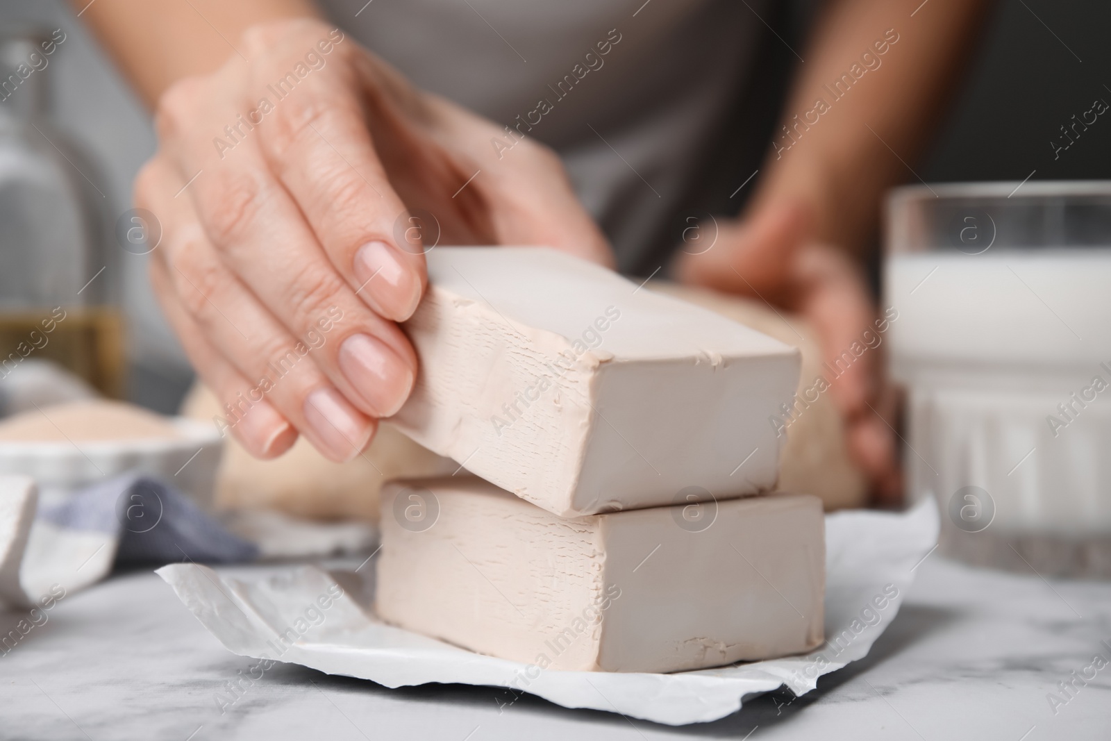 Photo of Woman taking bar of compressed yeast at table, closeup