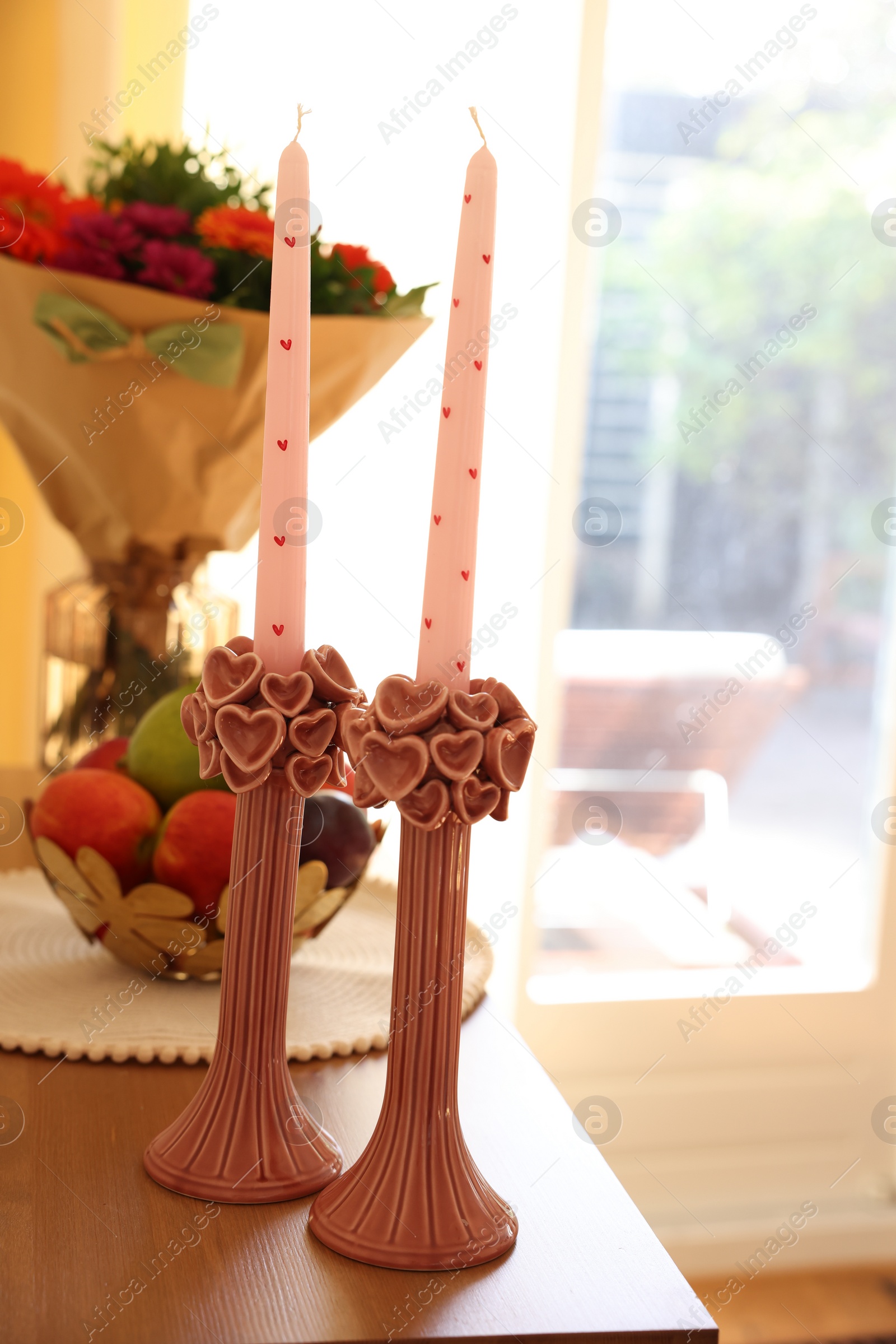 Photo of Bouquet of flowers, bowl with fresh fruits and candles on wooden table indoors, selective focus