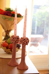 Photo of Bouquet of flowers, bowl with fresh fruits and candles on wooden table indoors, selective focus