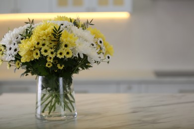 Vase with beautiful chrysanthemum flowers on table in kitchen, space for text. Interior design