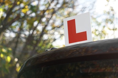 Photo of L-plate on car outdoors, space for text. Driving school