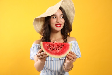 Beautiful young woman with watermelon on yellow background