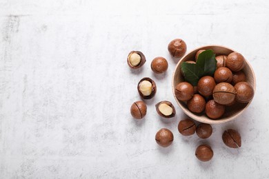 Photo of Delicious organic Macadamia nuts on white textured table, flat lay. Space for text