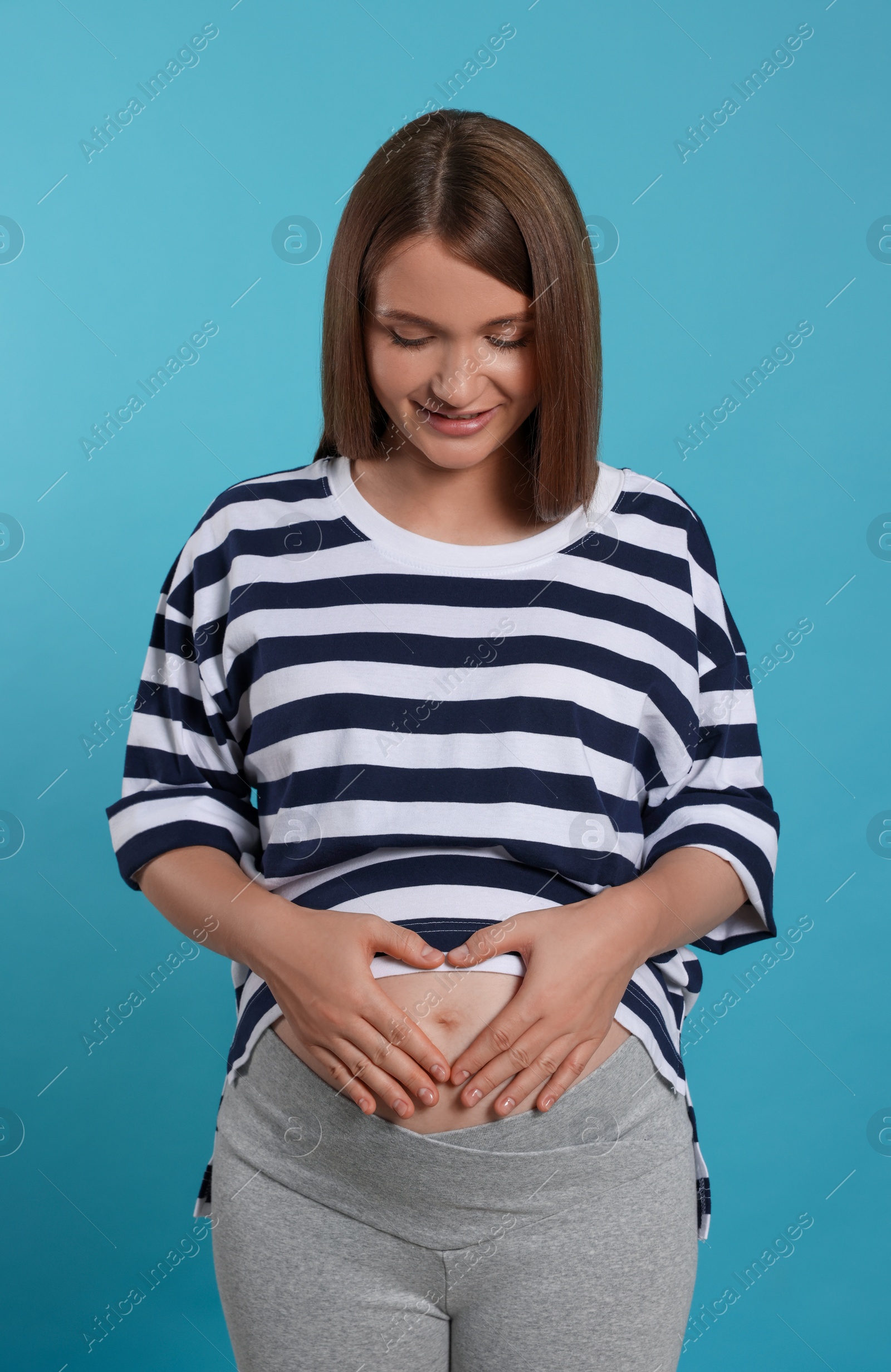 Photo of Happy young pregnant woman on light blue background