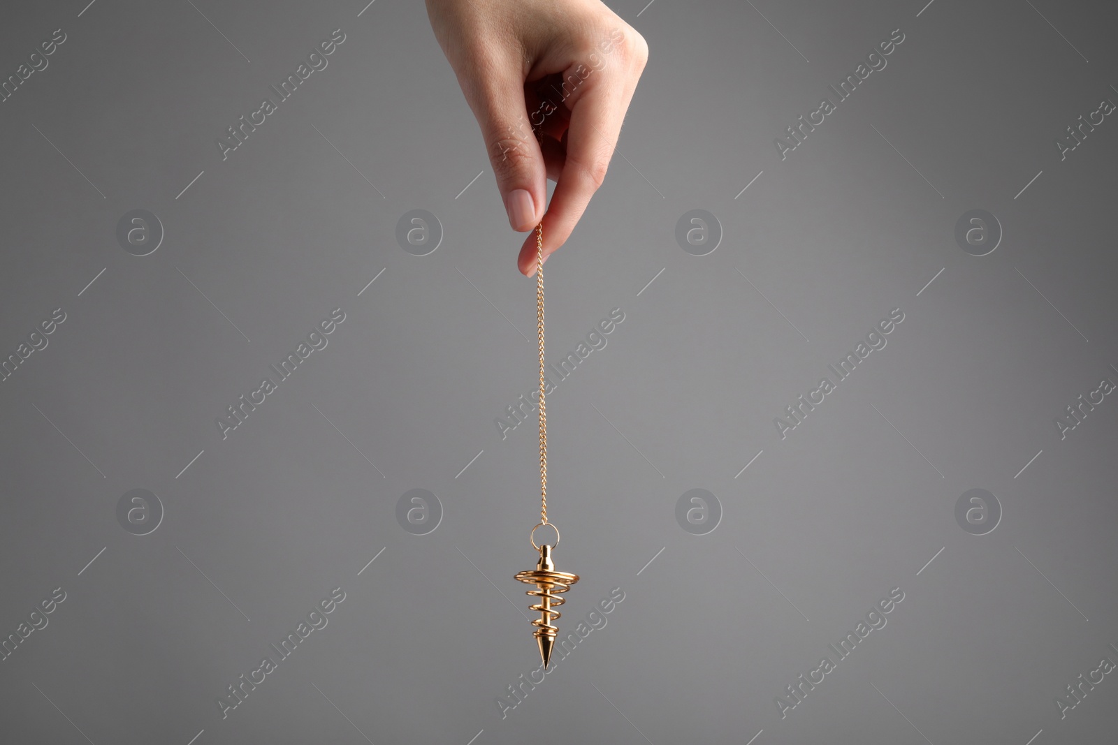 Photo of Psychotherapist with pendulum on grey background, closeup. Hypnotherapy session