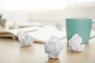 Sheets of crumpled paper and cup on wooden table, space for text