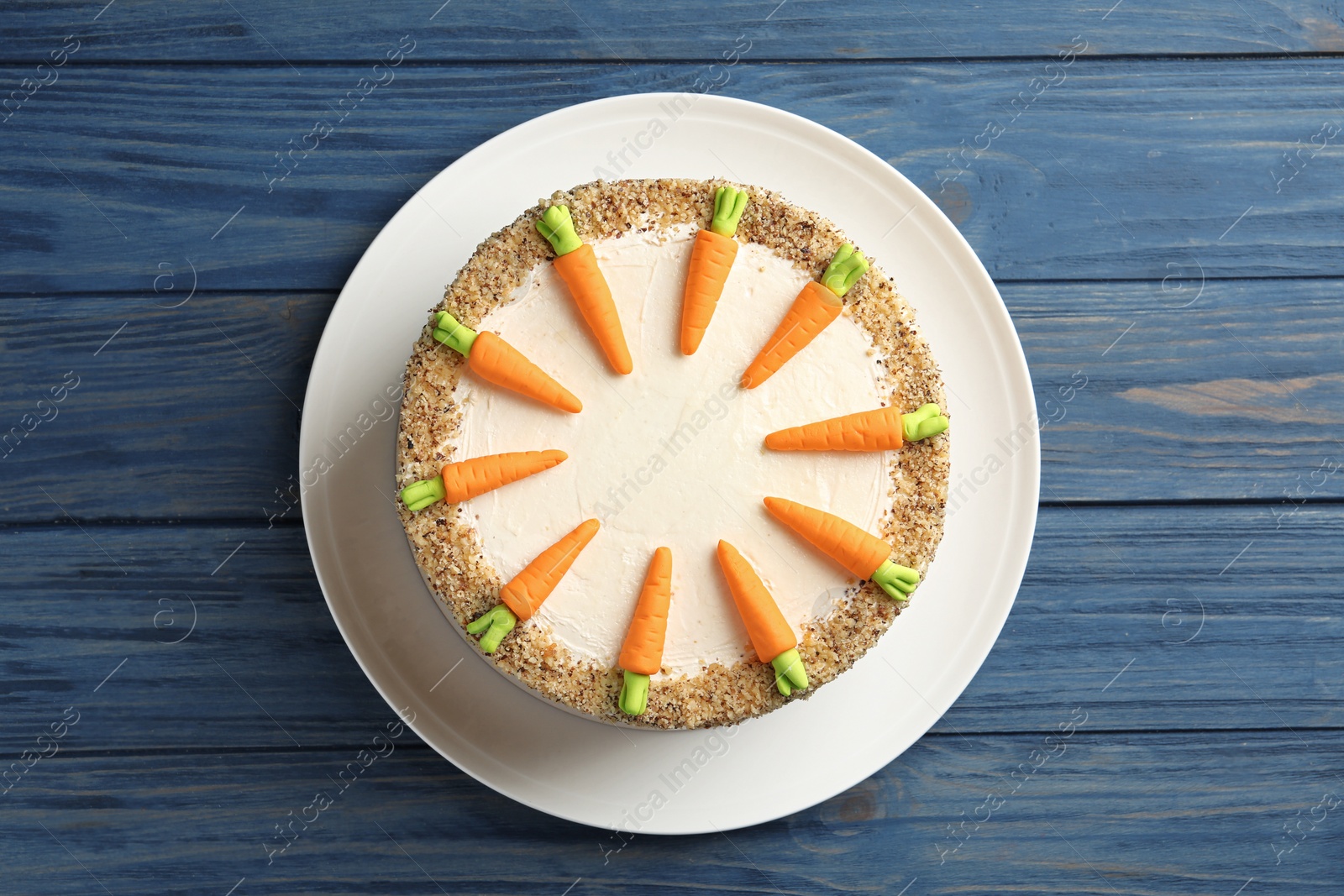 Photo of Dish with delicious carrot cake on blue wooden background, top view