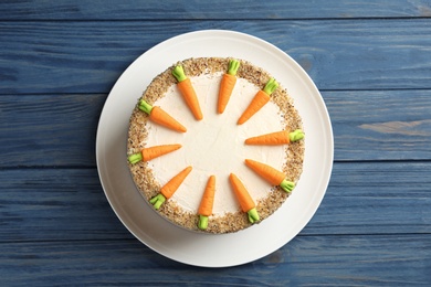 Dish with delicious carrot cake on blue wooden background, top view