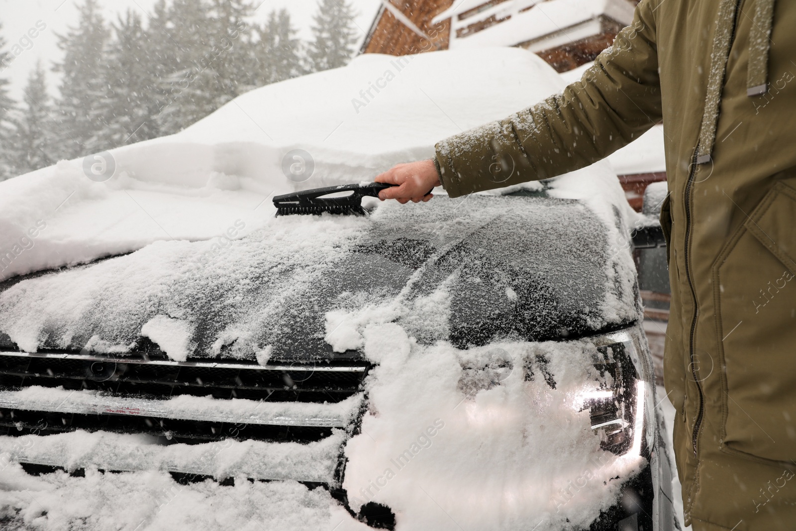 Photo of Young man cleaning snow from car outdoors on winter day, closeup