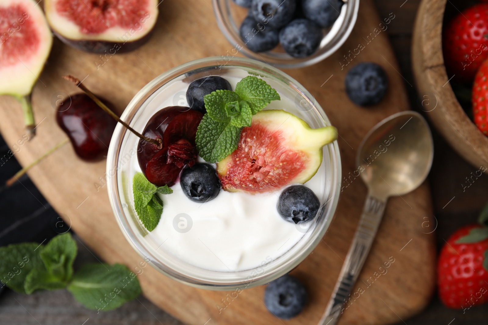 Photo of Glass with yogurt, berries and mint on wooden table, flat lay