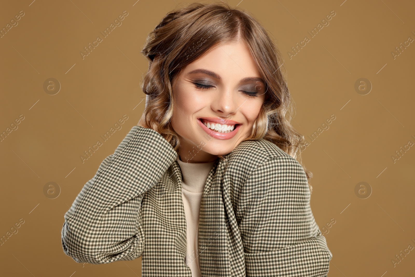 Photo of Portrait of young woman with beautiful makeup on light brown background