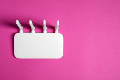 Photo of New white Wi-Fi router on pink background, top view. Space for text