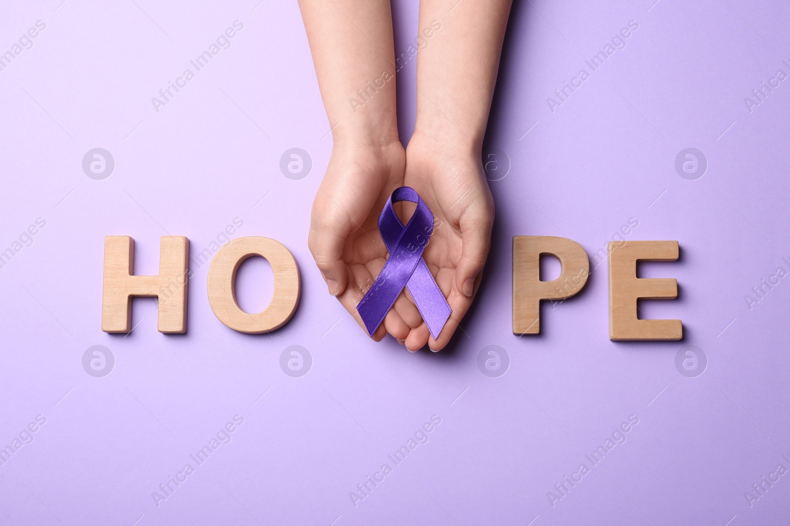 Photo of Woman with purple awareness ribbon and word HOPE made of wooden letters on violet background, top view
