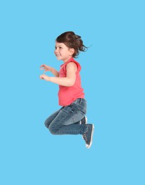 Happy cute girl jumping on light blue background