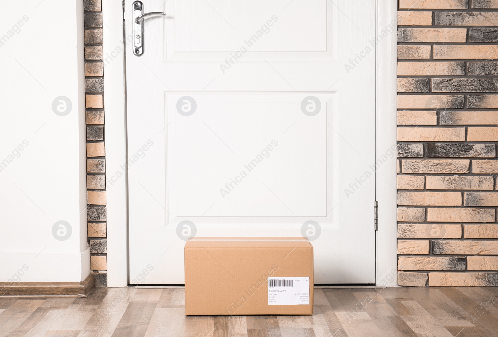 Photo of Cardboard parcel box on floor near apartment entrance. Mockup for design