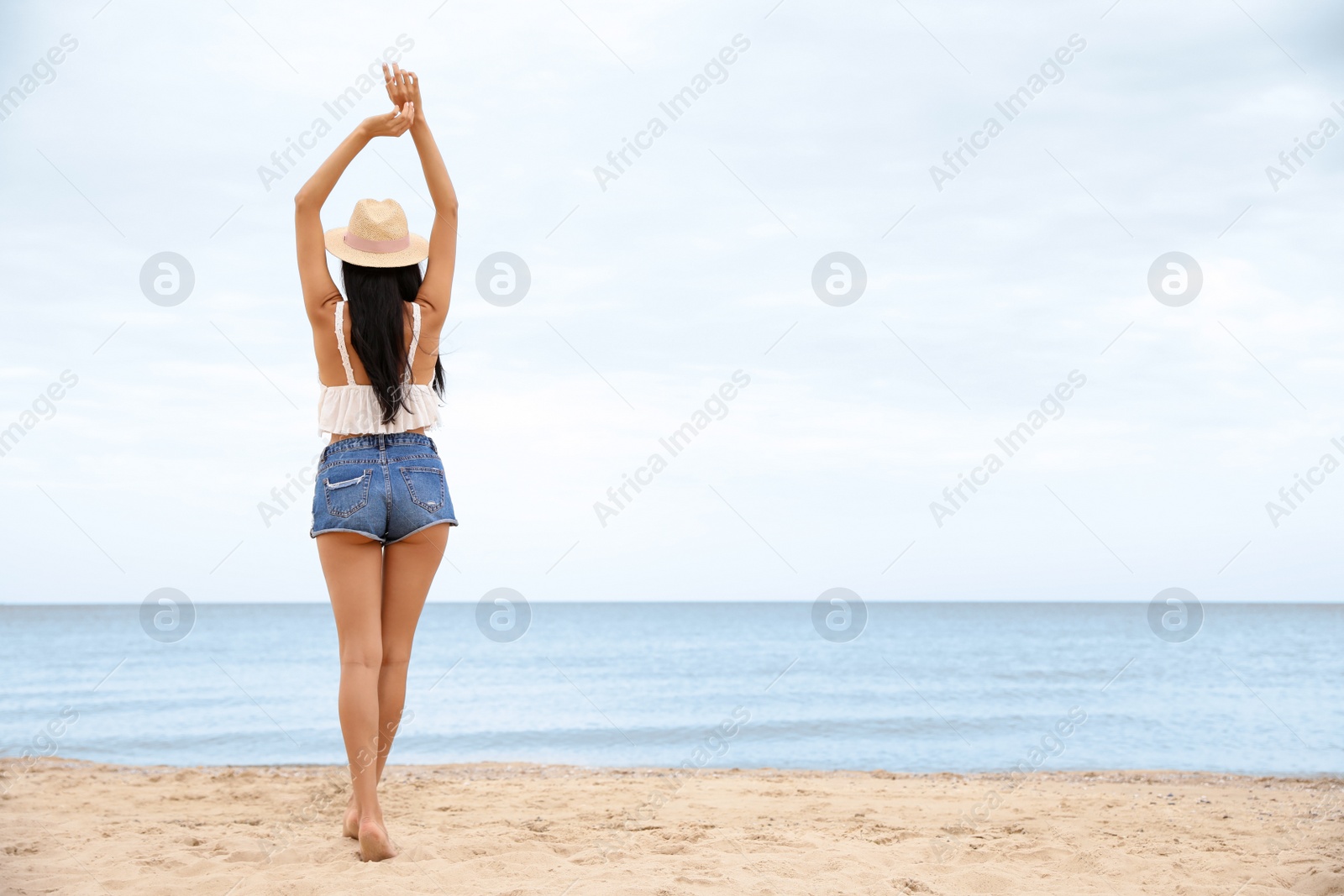 Photo of Beautiful young woman on beach, back view. Space for text