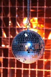 Photo of Shiny disco ball against foil party under color lights