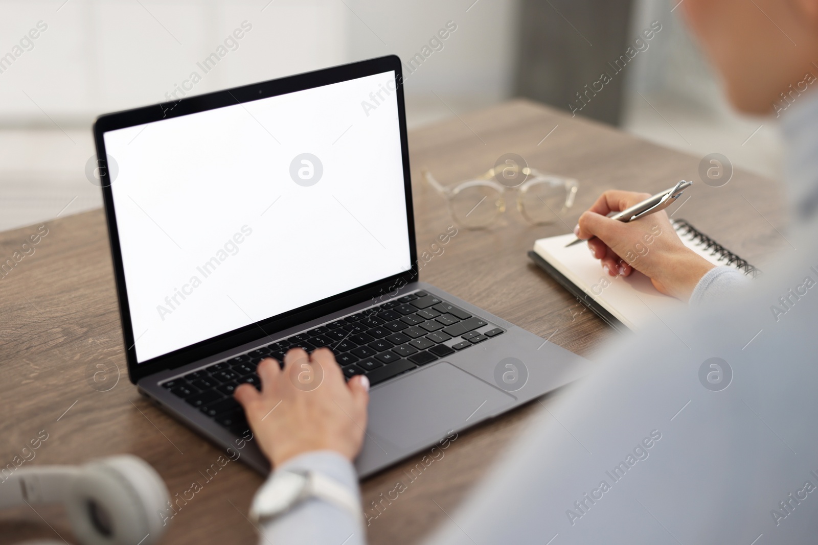 Photo of Young woman watching webinar at table indoors, closeup