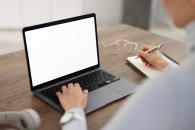 Photo of Young woman watching webinar at table indoors, closeup