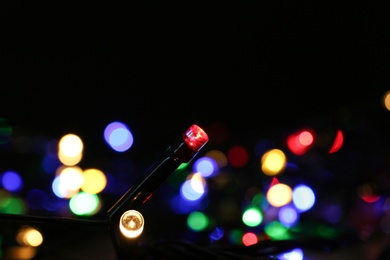 Photo of Colorful Christmas lights on dark background, closeup view