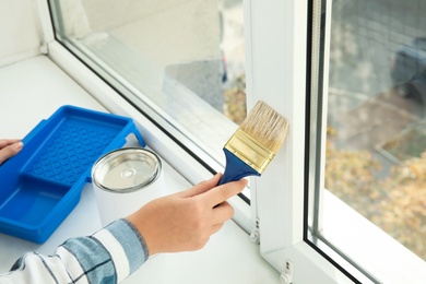 Photo of Woman painting window frame at home, closeup