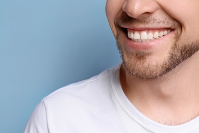 Young man with beautiful smile on grey background. Teeth whitening