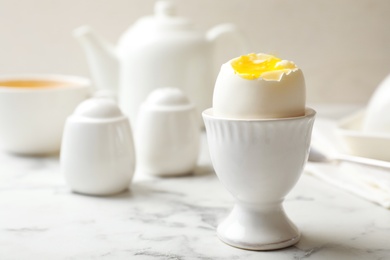 Photo of Holder with soft boiled egg on table. Space for text