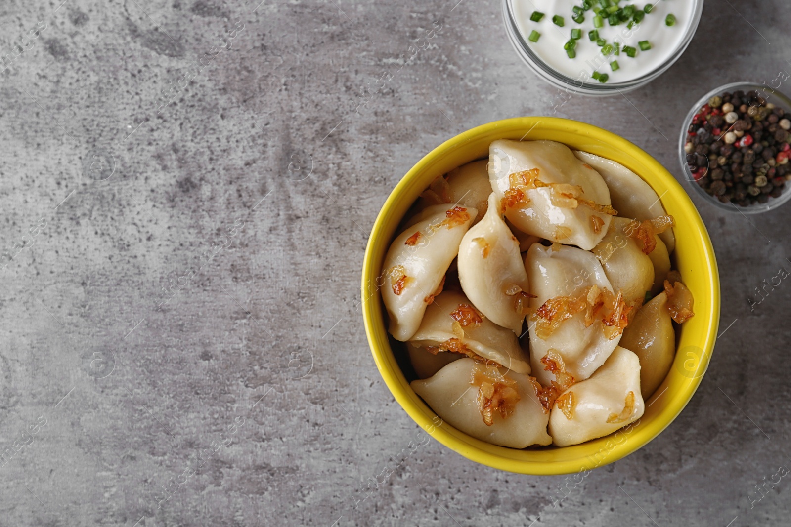 Photo of Delicious cooked dumplings with fried onion on grey table, flat lay. Space for text