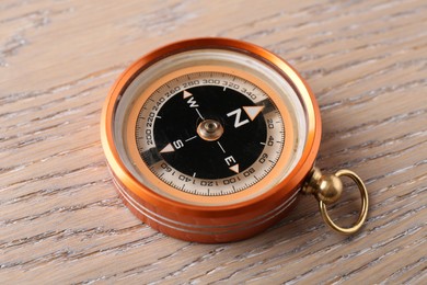 Photo of One compass on wooden table, closeup. Tourist equipment